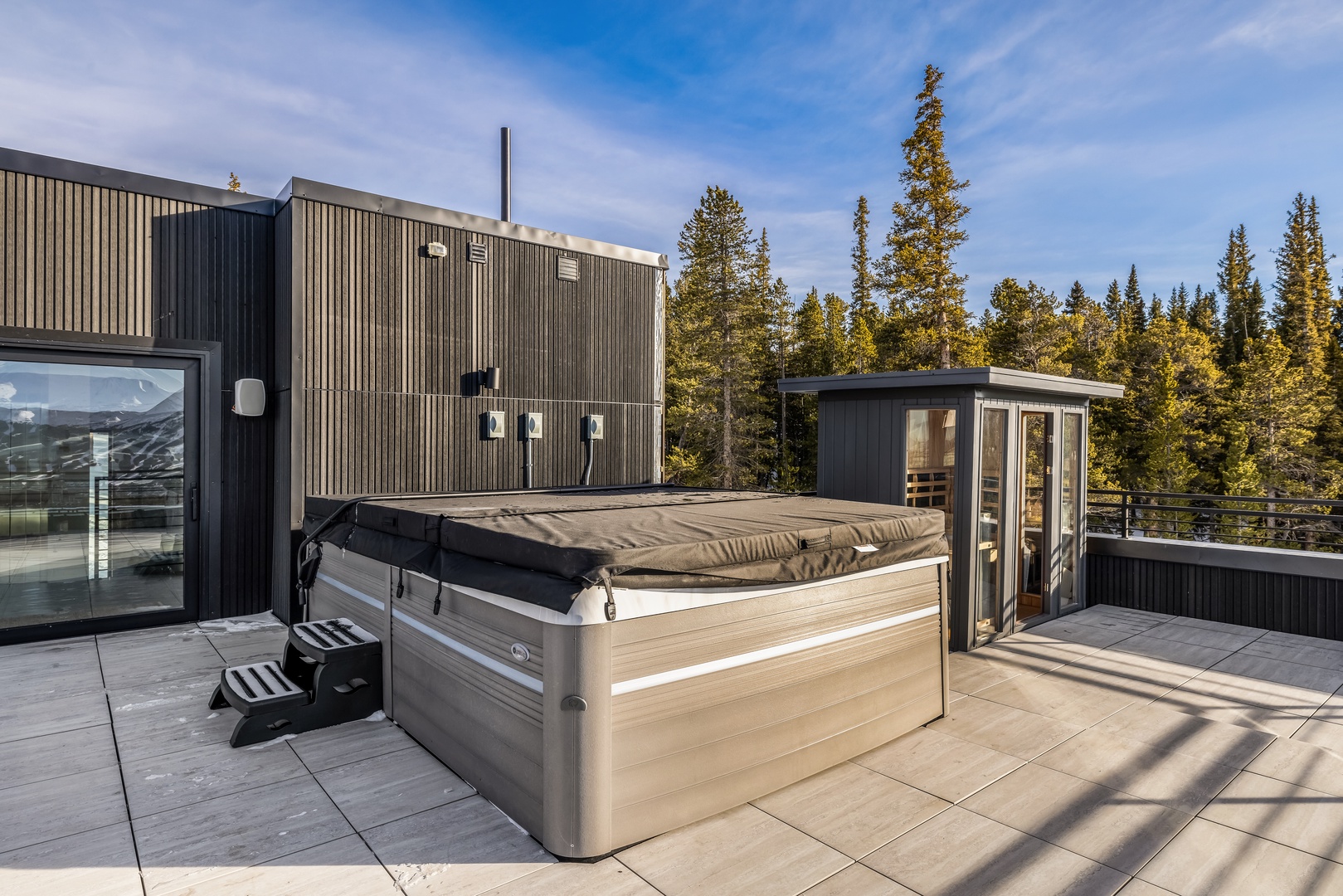 Unwind in your private hot tub on this stunning rooftop terrace, surrounded by towering evergreens and endless mountain views.