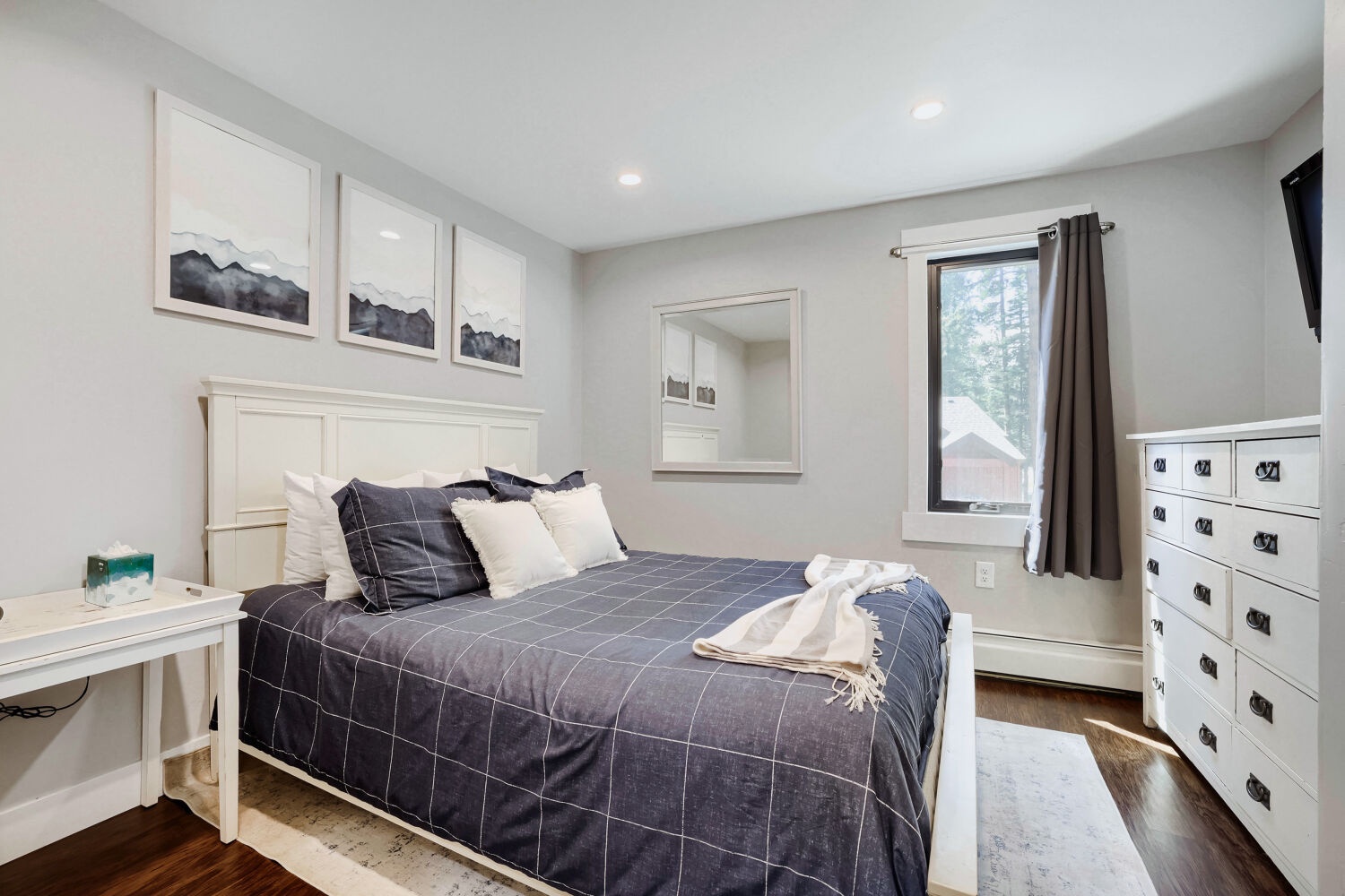 Your serene bedroom retreat features a crisp white aesthetic with navy accents, a plush bed with layered linens, and natural light streaming through the window. Everything you need for restful, rejuvenating sleep.