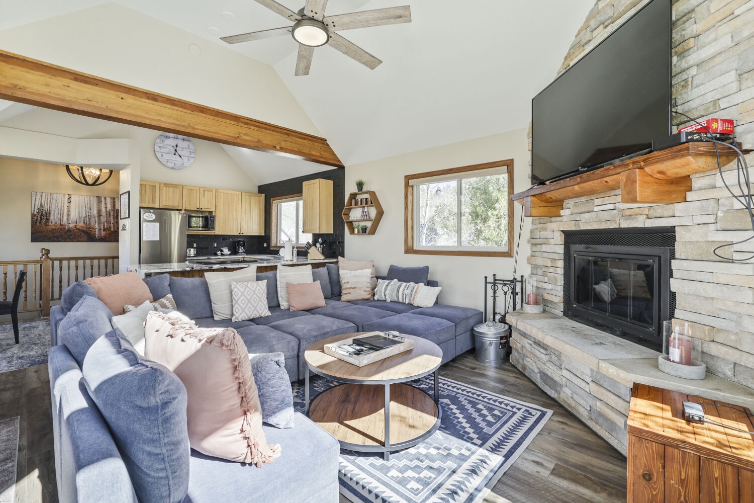 Settle into your cozy living space with plush seating and a warm fireplace, where vaulted ceilings and natural light create an inviting retreat after a day exploring.