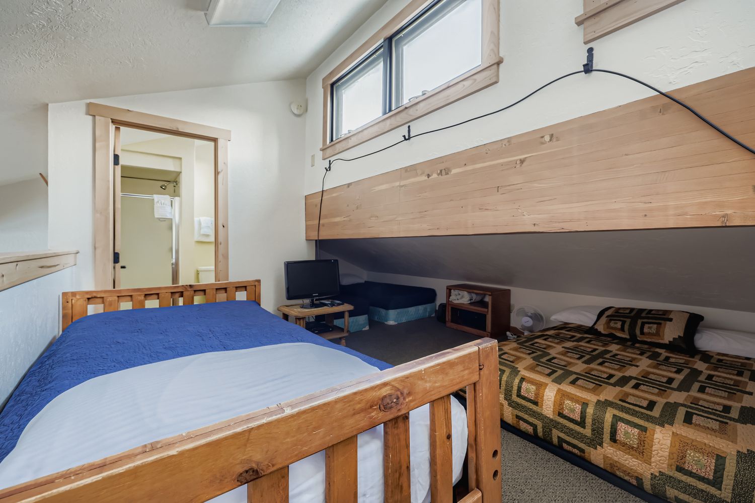 Cozy bunk bed room with natural wood details and TV entertainment, perfect for your mountain getaway sleep.