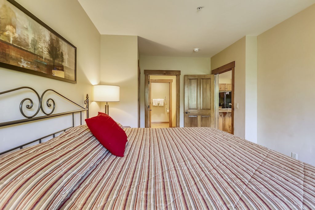 Sink into this inviting bed with its elegant striped linens and vibrant red accent pillow, perfectly positioned near your private bathroom.