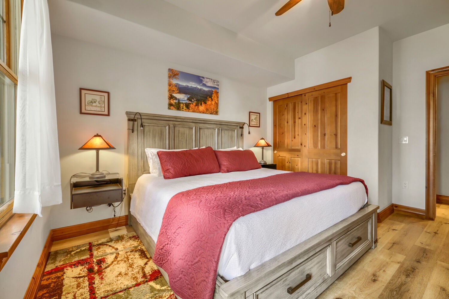 Sink into crisp white linens dressed with a rich crimson runner, and let the warm glow of bedside lamps melt away your day. Your cozy, wood-accented retreat awaits.