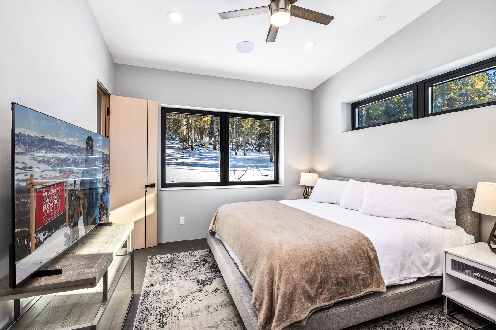 Wake up to snowy mountain views from your cozy bedroom with plush bedding, modern amenities, and peaceful forest scenery right outside your window.