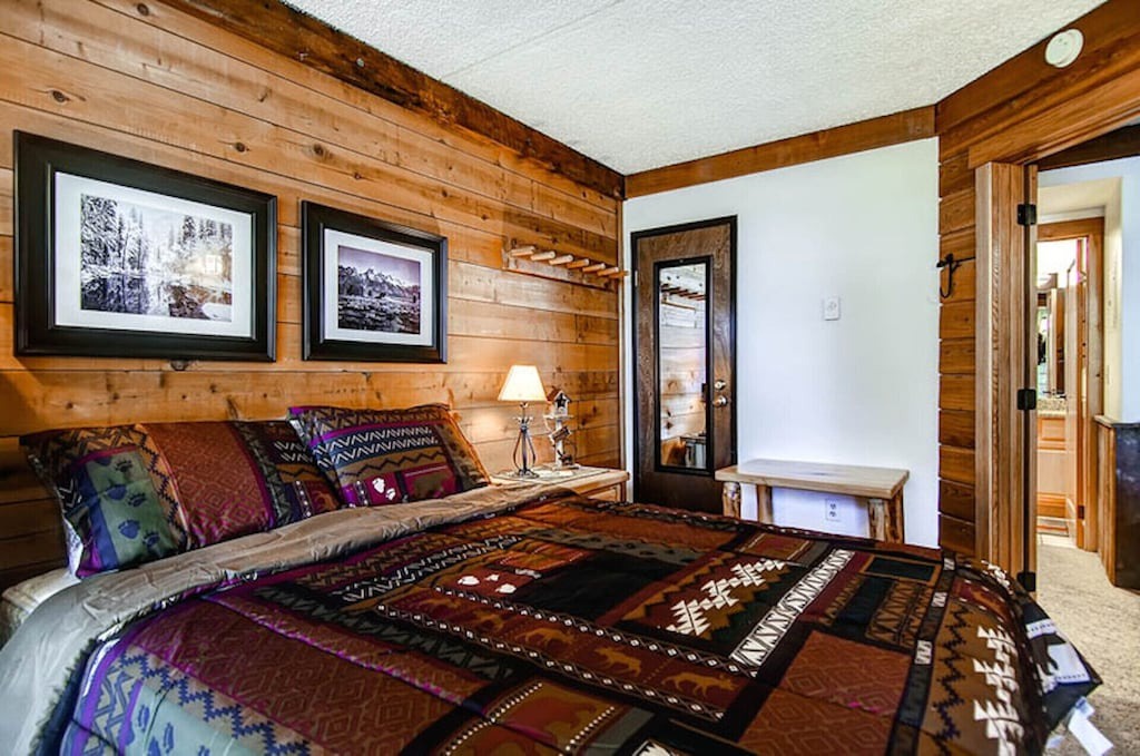 Drift off in your cozy log cabin bedroom, where warm wood walls and vibrant native patterns create a peaceful mountain retreat.
