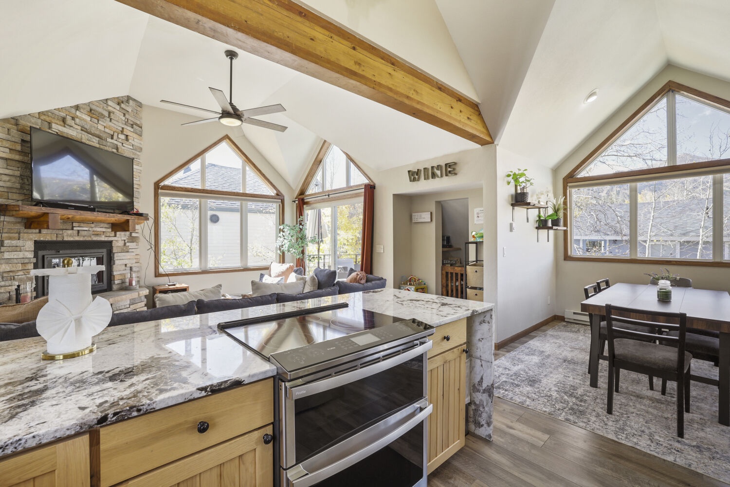 A soaring, sunlit space flows seamlessly from the kitchen to the living room, where exposed beams and natural light create a warm, inviting retreat for your mountain getaway.