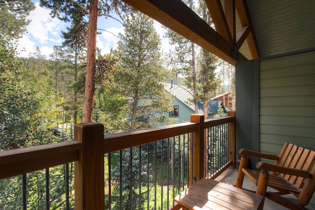 Your private balcony overlooks towering pines and neighboring cabins, creating the perfect spot for morning coffee surrounded by forest serenity.