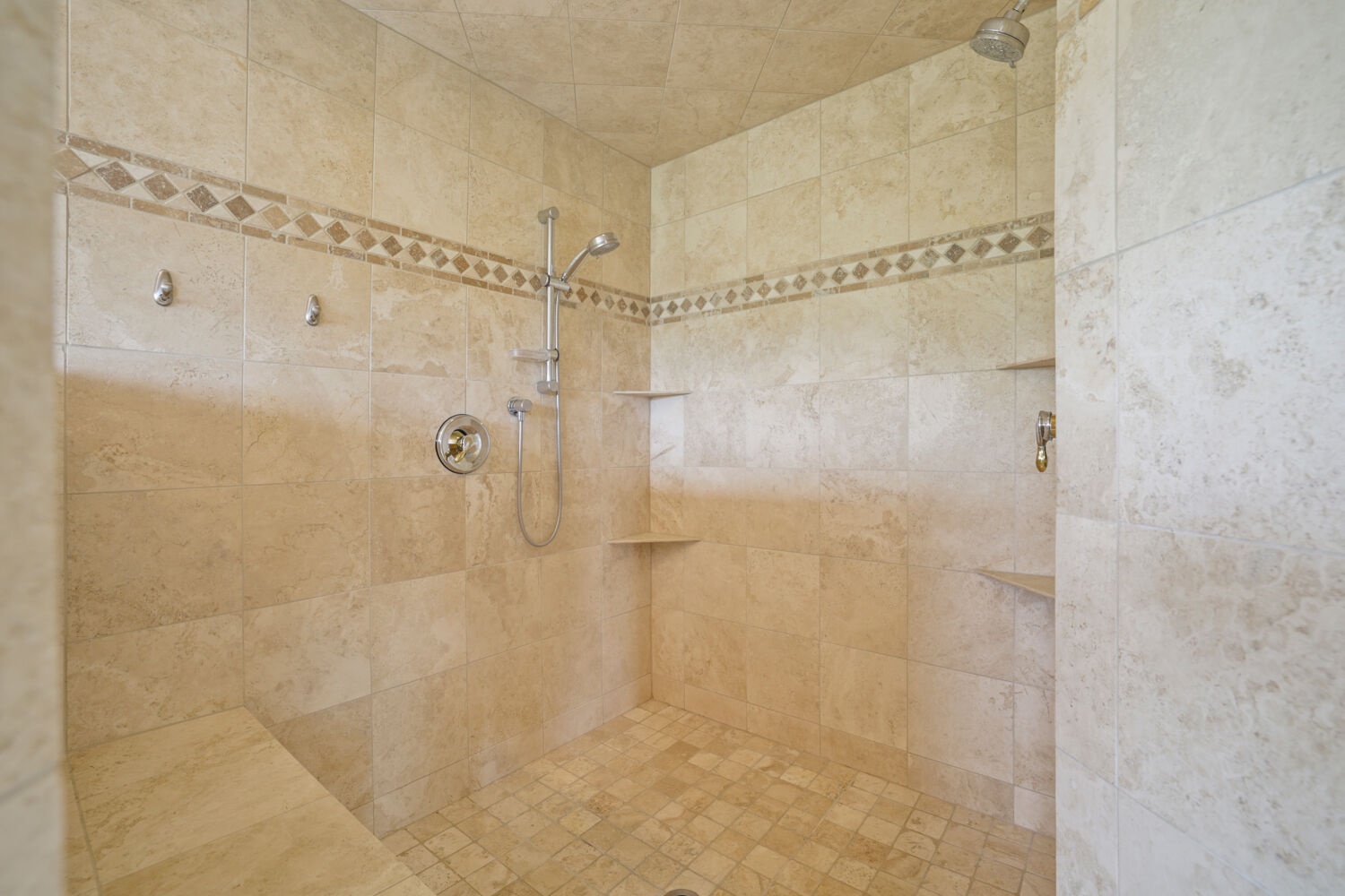 Unwind in your spacious walk-in shower, beautifully tiled with elegant neutral stone and accented with mosaic detailing. The handheld and overhead fixtures offer a soothing, spa-like experience.