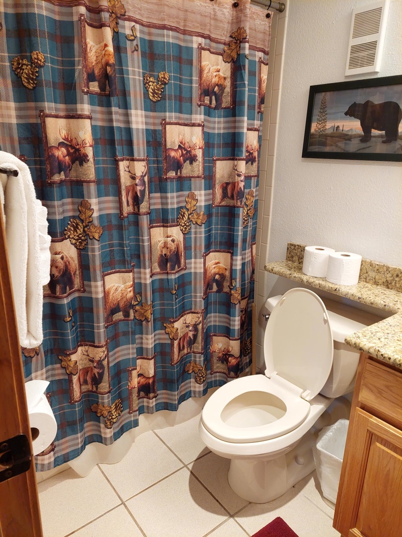 Your private bathroom features wilderness-themed décor with bear artwork, creating a cozy cabin atmosphere for your mountain getaway.