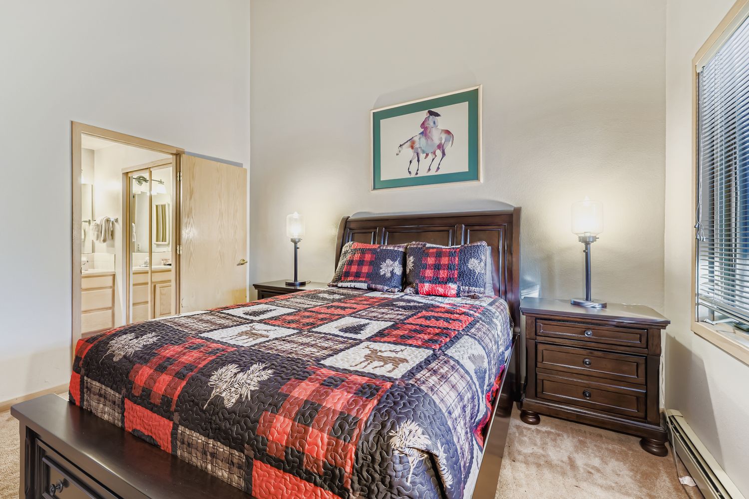 Unwind in your cozy bedroom featuring a rustic plaid quilt and warm wood furnishings that create the perfect mountain retreat atmosphere.
