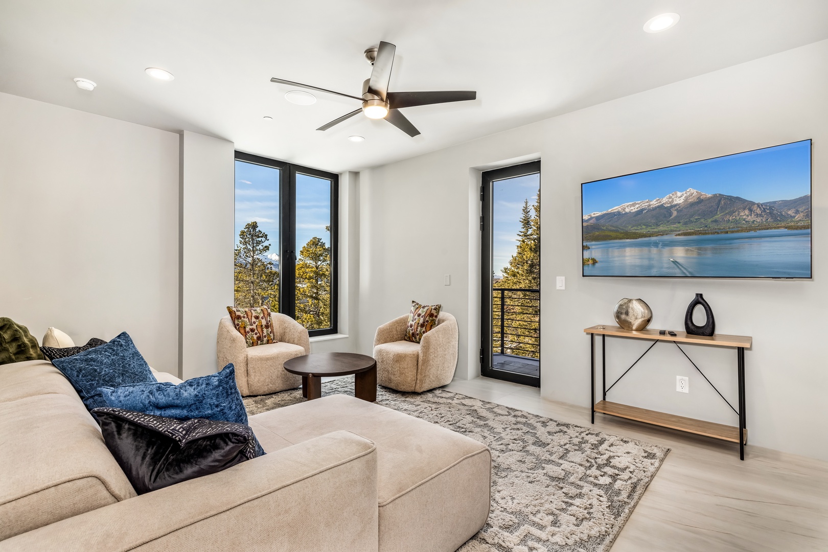 Relax in this bright living space with mountain views through floor-to-ceiling windows. Sink into plush seating while enjoying the ceiling fan's gentle breeze.