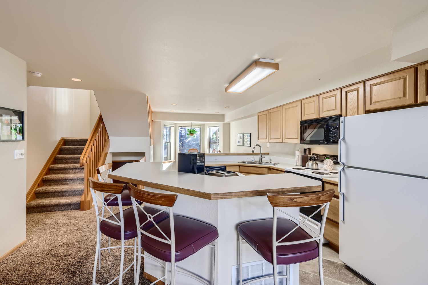 Your spacious kitchen features warm wood cabinetry, modern appliances, and a breakfast bar where you can enjoy morning coffee.