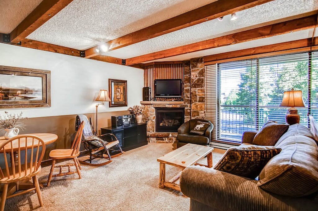 Sink into cozy comfort in this warm living room, where exposed beams and a crackling fireplace create your perfect mountain retreat.