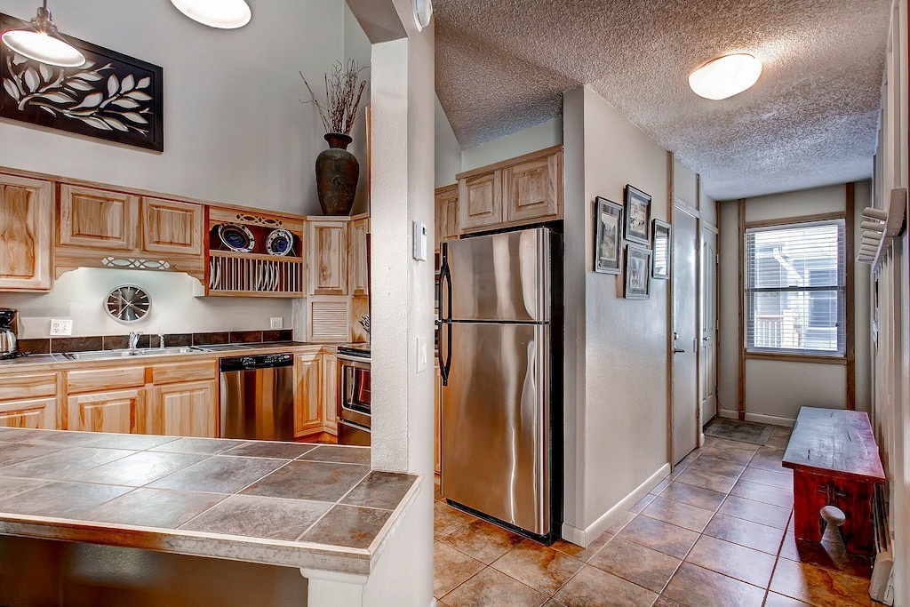 Your fully equipped kitchen features beautiful wood cabinets, stainless steel appliances, and a spacious tile island for effortless meal preparation.