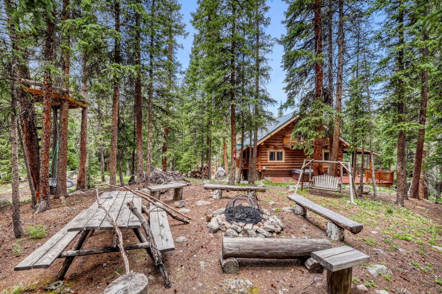 A peaceful forest-side log cabin awaits, with rustic picnic benches and fire pit perfect for starlit evenings and s'mores under towering pines.