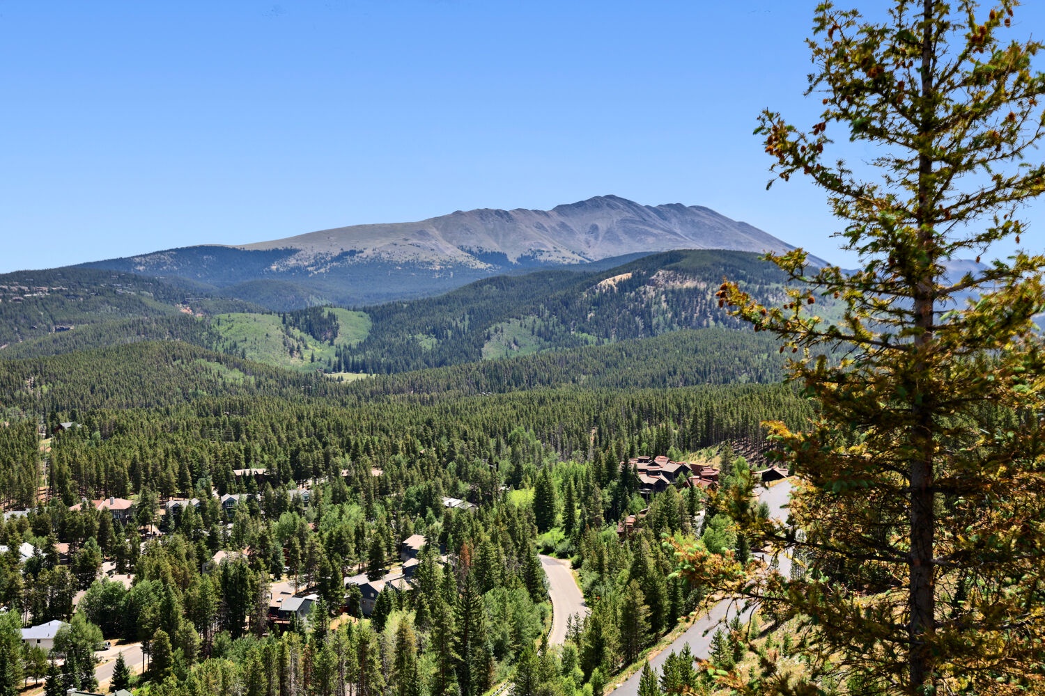 Mountain scenery and forested neighborhood surrounding the property, offering a serene alpine setting beneath expansive blue skies.