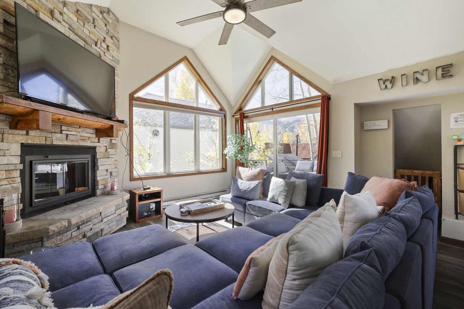 Sink into plush seating and unwind by the stone fireplace while soaking in natural light and mountain views through the vaulted windows.