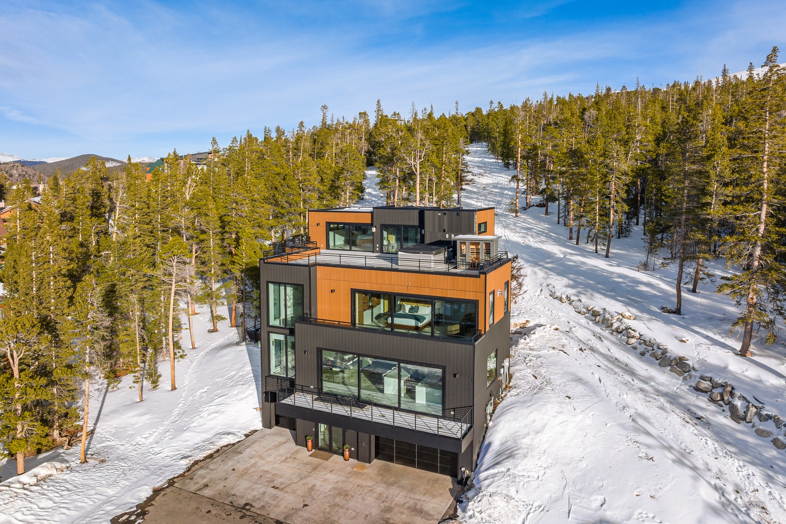 Modern mountain retreat nestled among snow-covered pines with ski slopes nearby, offering stunning winter wilderness views.