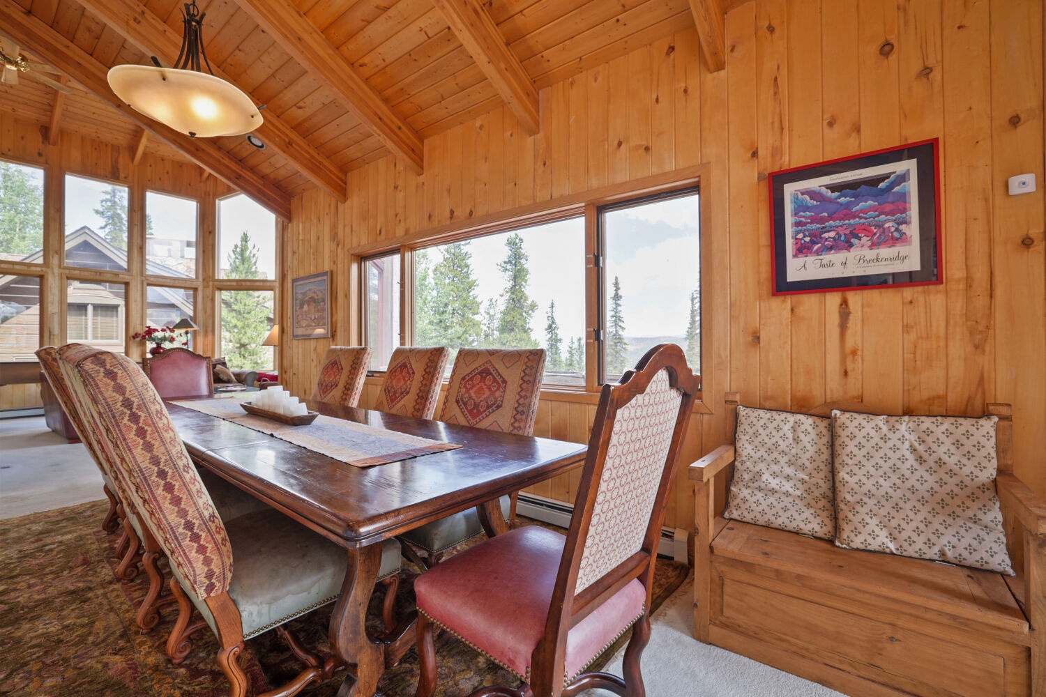 Gather around the dining table where rustic wood meets mountain charm. Large windows frame evergreen views, filling your space with natural light and alpine beauty.