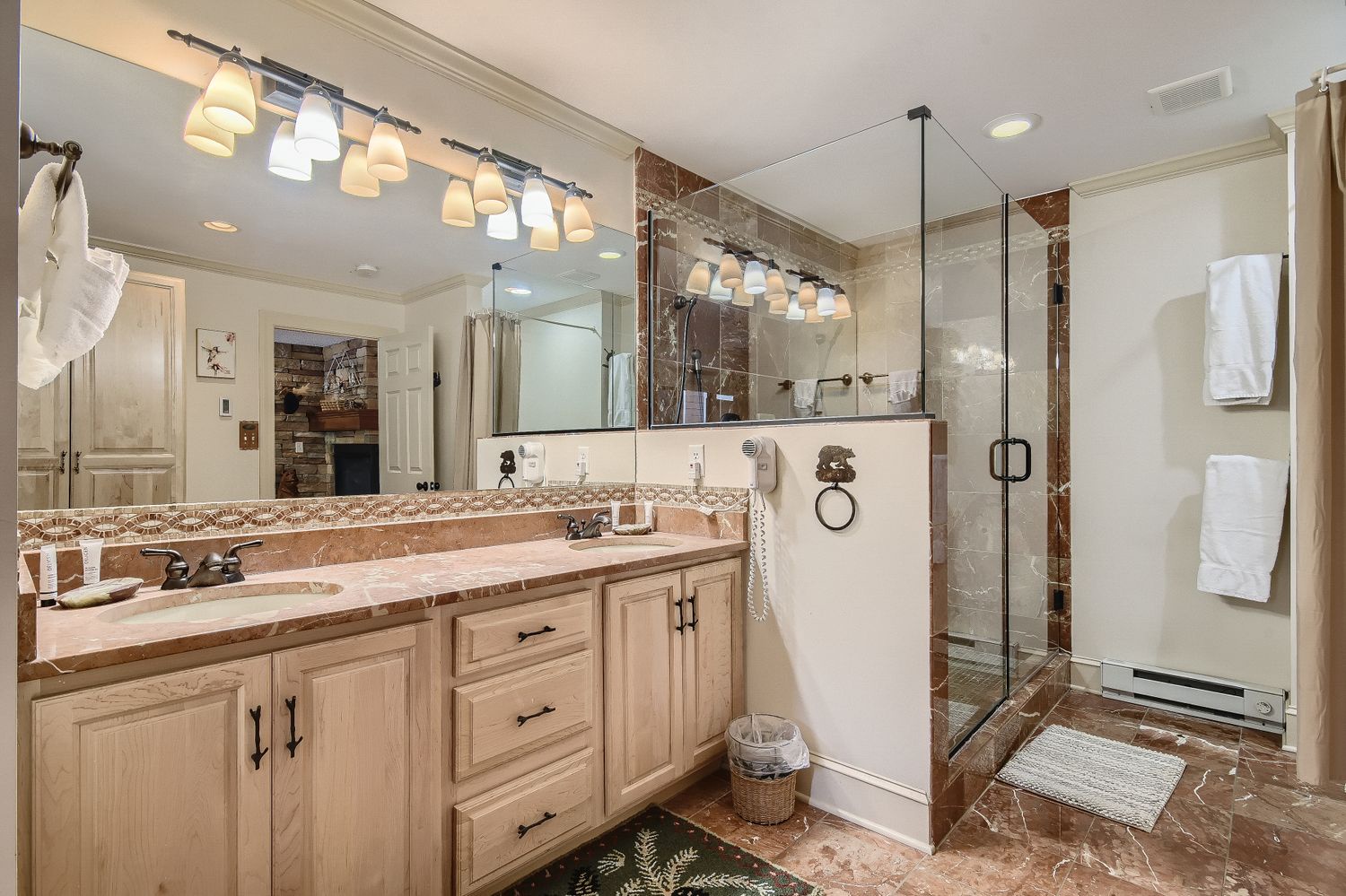 Luxurious bathroom with dual vanities, elegant lighting, and spacious glass shower creates your perfect retreat for refreshing starts.