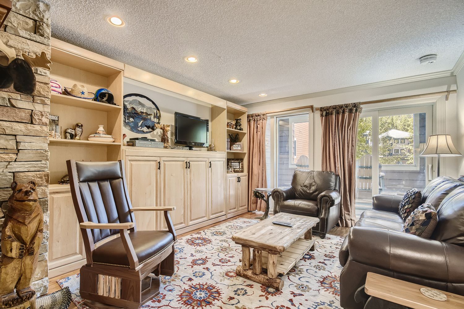 Sink into plush leather seating by your crackling fireplace, where built-in shelving showcases local treasures and mountain views frame your peaceful retreat.