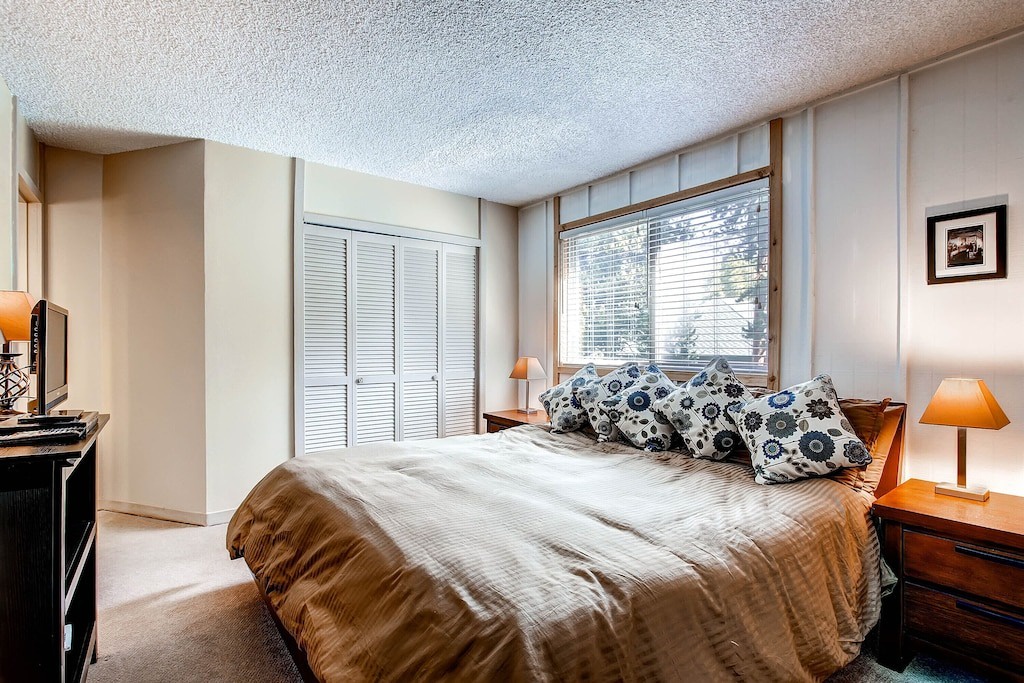 Sink into this cozy bedroom where warm lamps create perfect reading ambiance and your forest view window promises peaceful mornings.