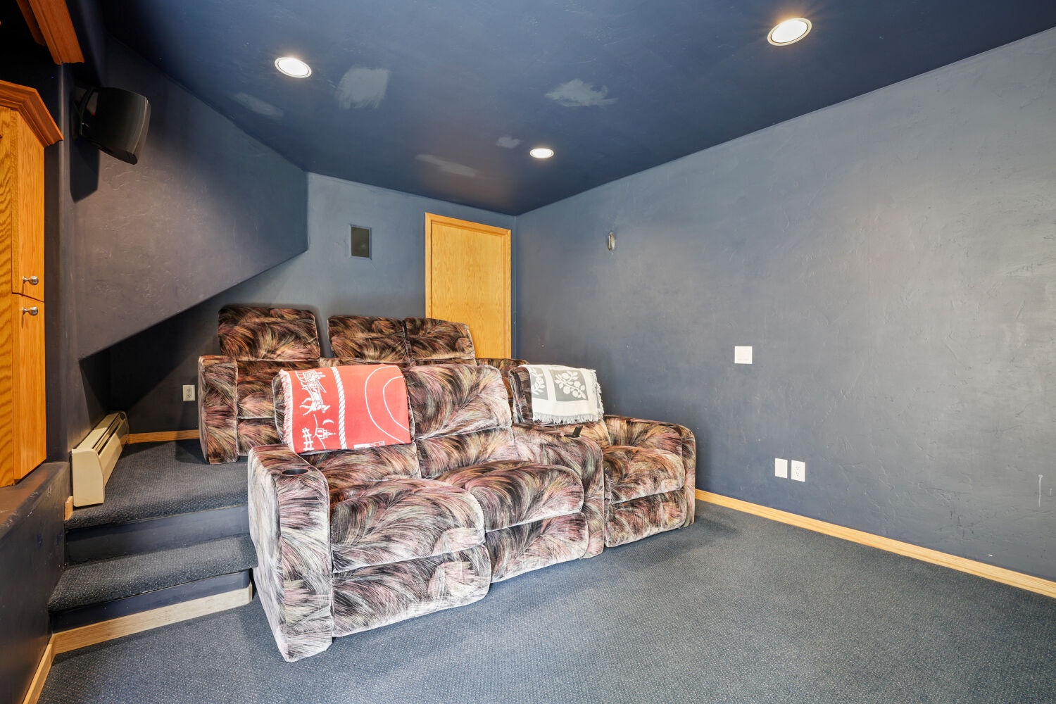 Cozy theater room with tiered seating and bold navy ceiling lets you settle in for movie nights and big games without ever leaving home.