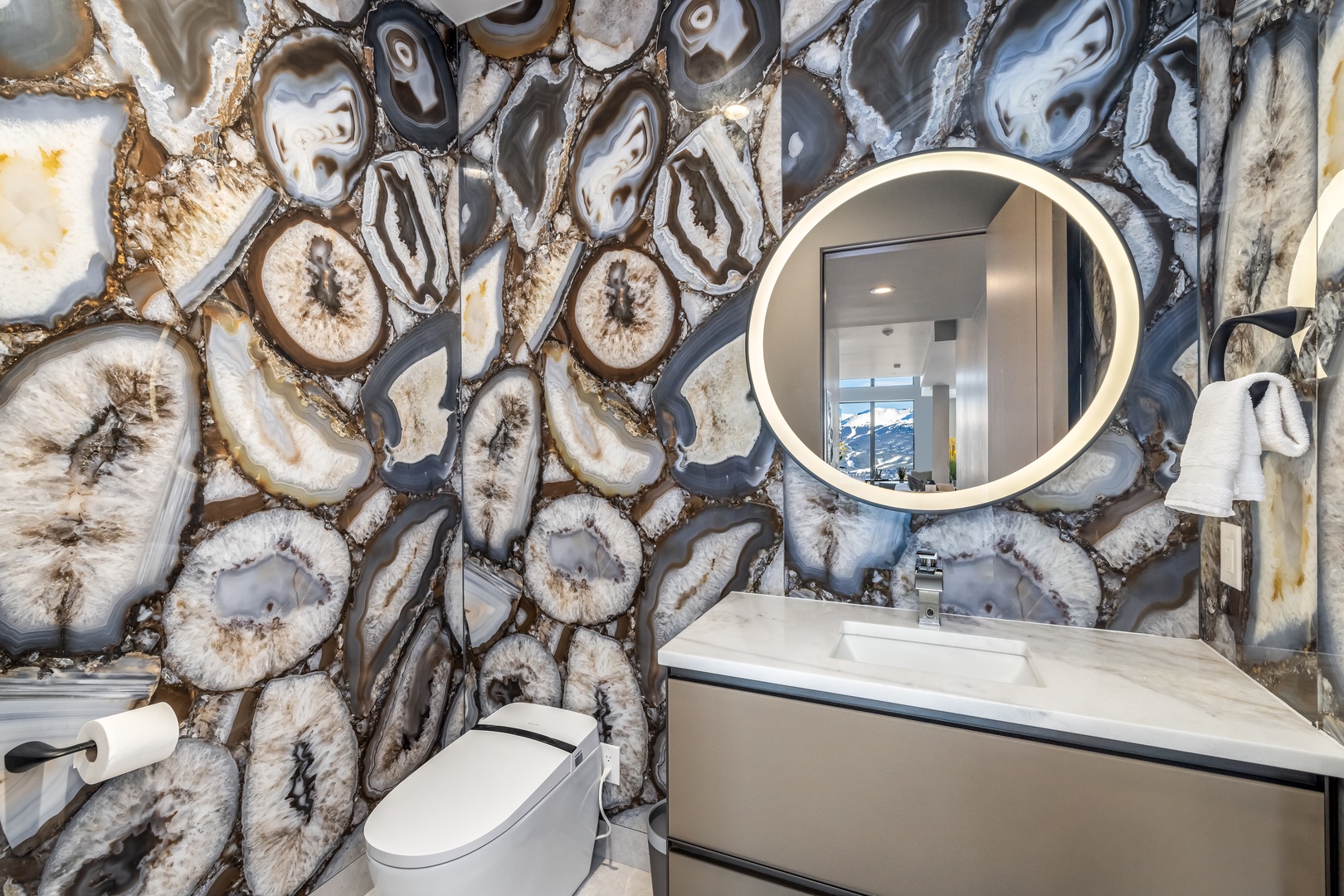 Admire the stunning agate stone wall while getting ready in this luxurious powder room featuring modern fixtures and elegant lighting.