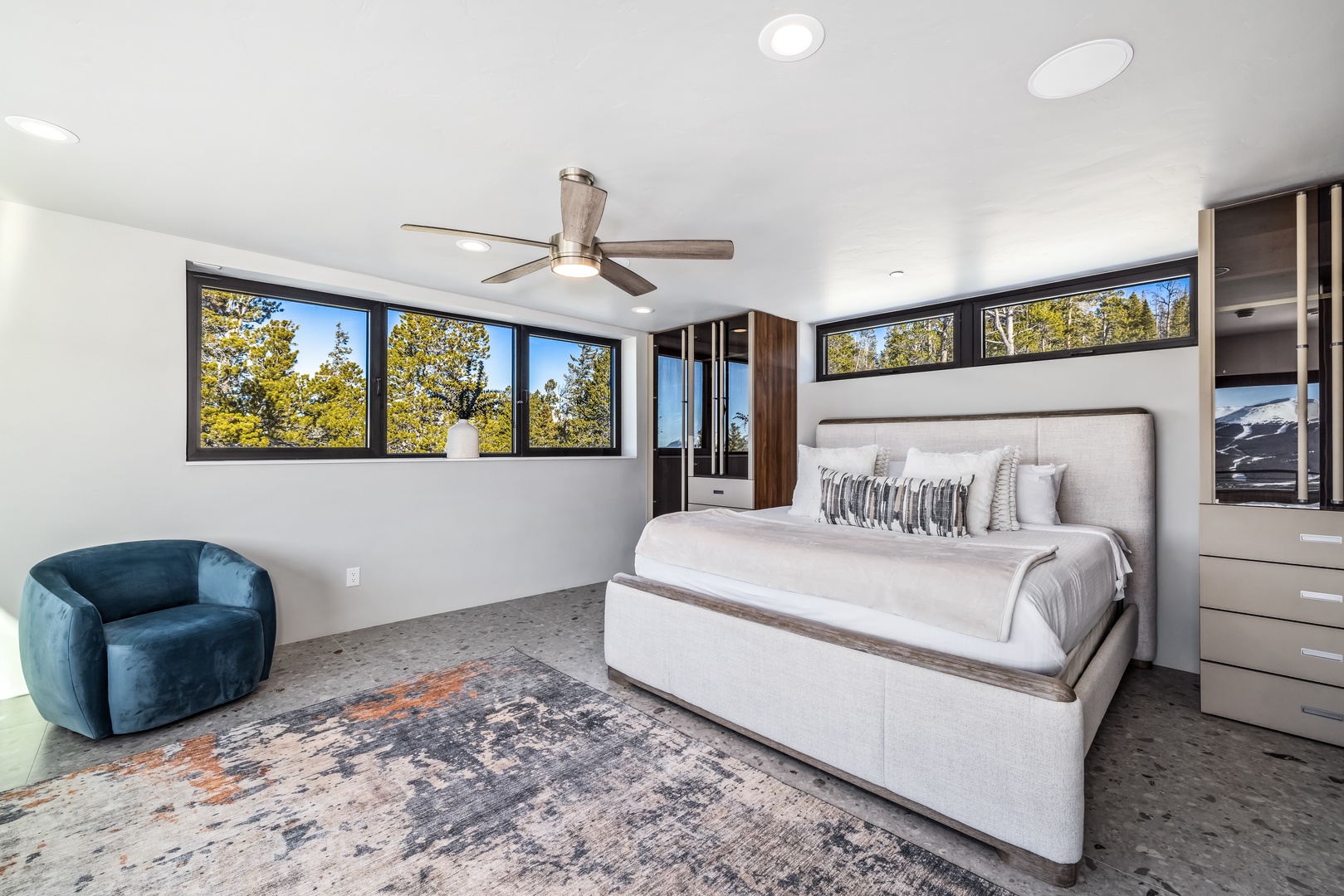 Relax in your spacious master bedroom with plush bedding, modern furnishings, and natural light streaming through large windows.