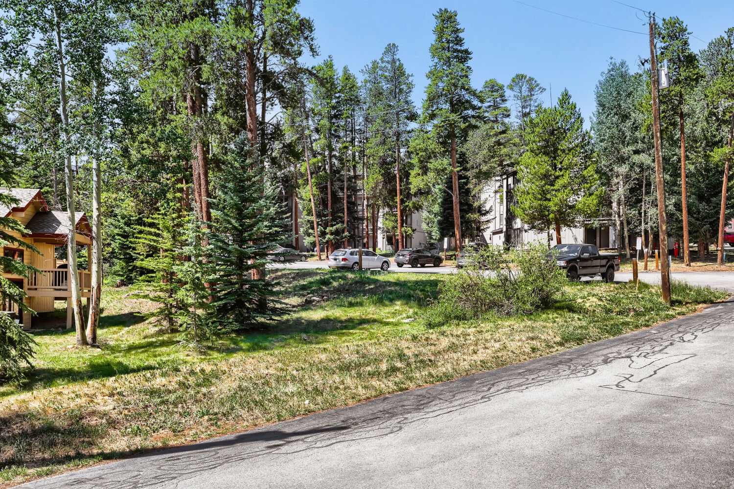 The property is nestled in a serene, tree-lined neighborhood with towering pines and aspens, offering a peaceful mountain retreat setting with convenient parking.
