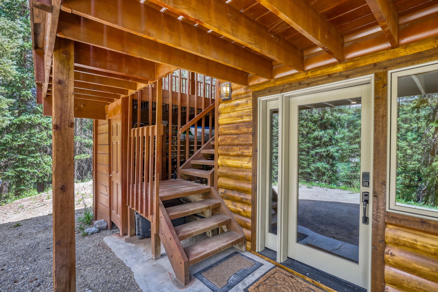 Your private entrance welcomes you beneath warm wooden beams, opening to a tranquil forest retreat where nature surrounds your getaway.