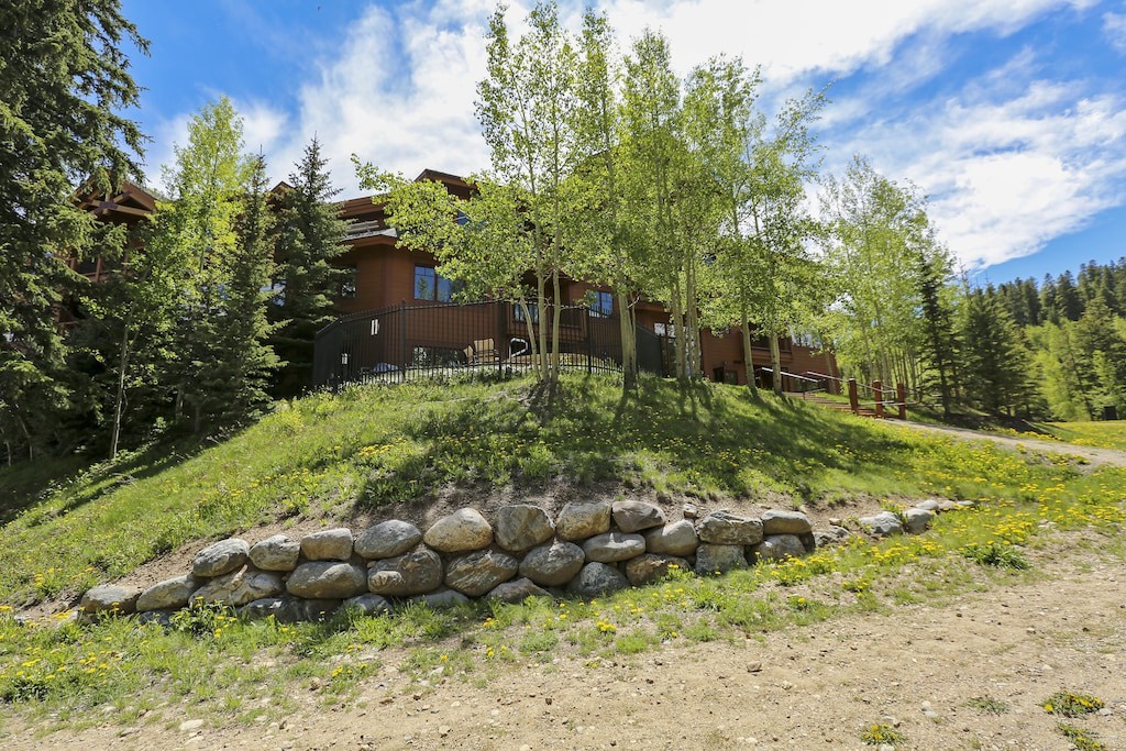 Mountain retreat nestled among towering trees and natural stone landscaping, offering peaceful seclusion in pristine wilderness surroundings.