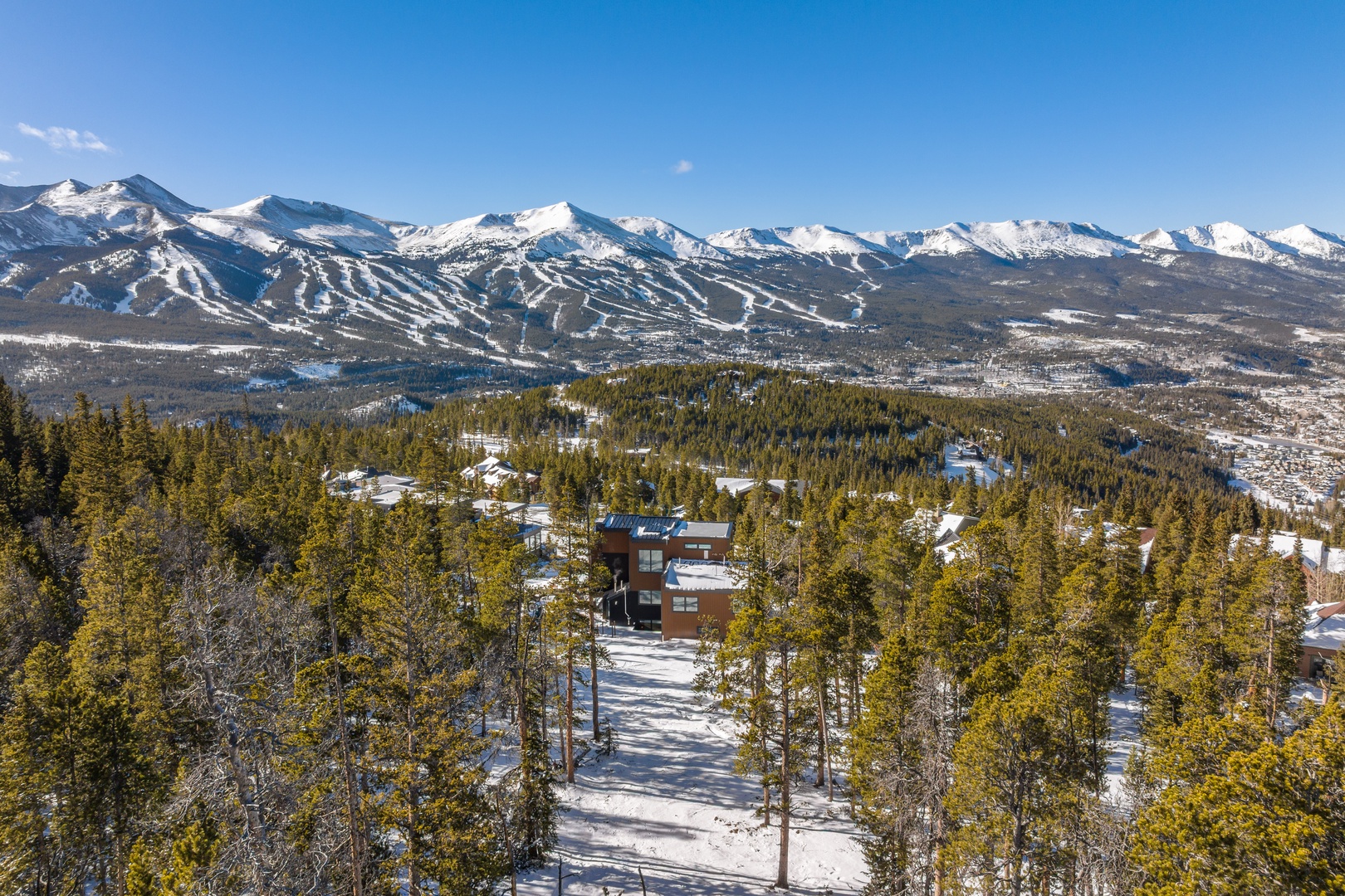 Stunning aerial perspective showcasing a mountain retreat nestled among snow-covered peaks and evergreen forests.