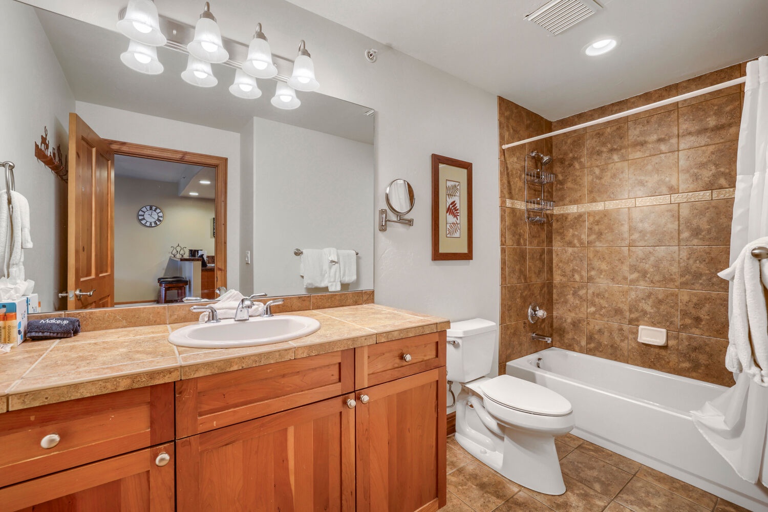 Step into your elegantly tiled bathroom with warm wood accents, featuring a spacious tub-shower combo and vanity with plenty of counter space—your personal retreat after every adventure.