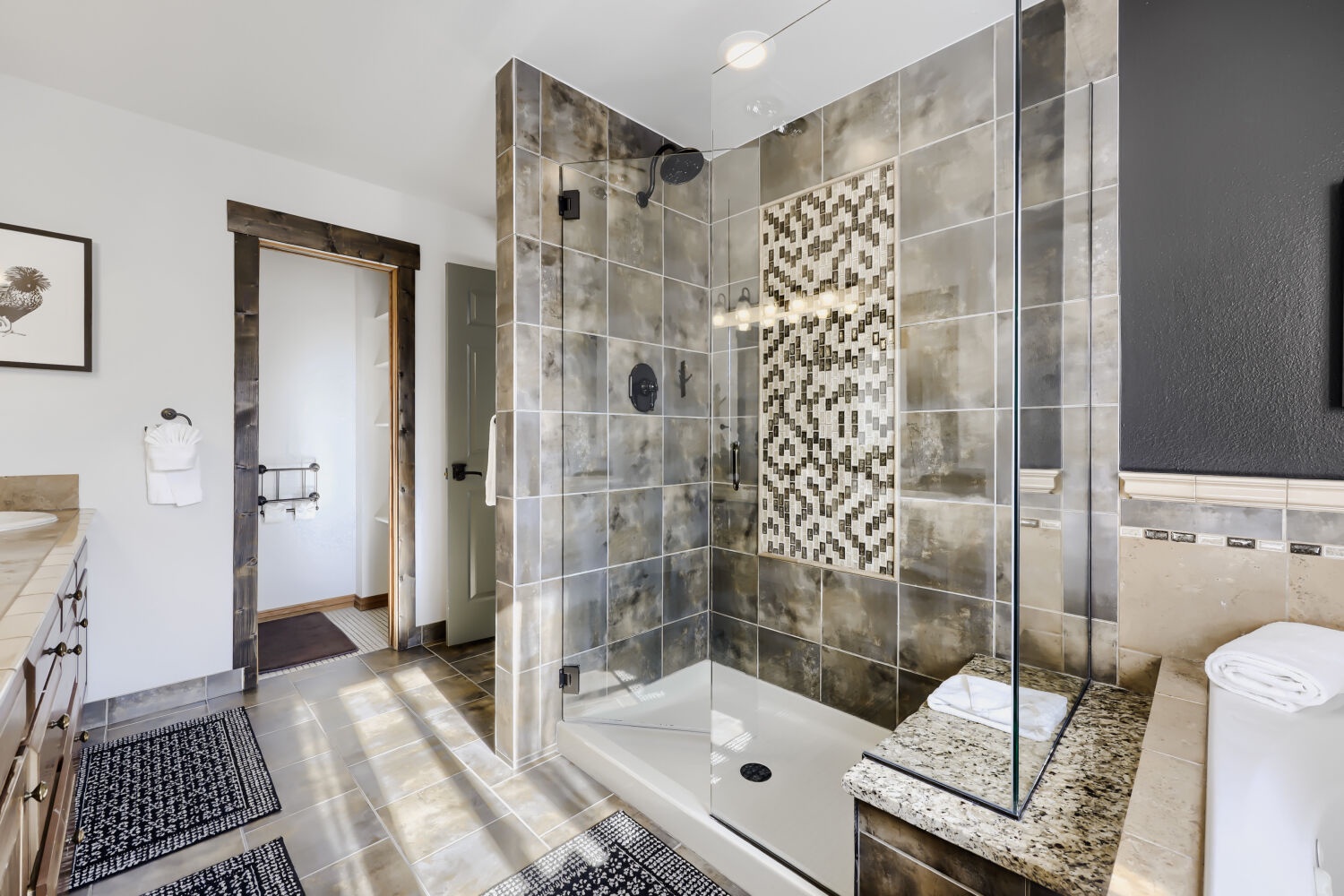 Slip into your private oasis featuring a stunning tiled shower with rainfall showerhead and mosaic accent wall. Plush towels await you after a relaxing rinse.