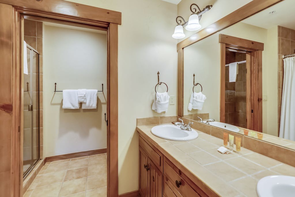 Step into your private bathroom sanctuary with warm wood accents and tile floors, where fresh towels await your relaxation.