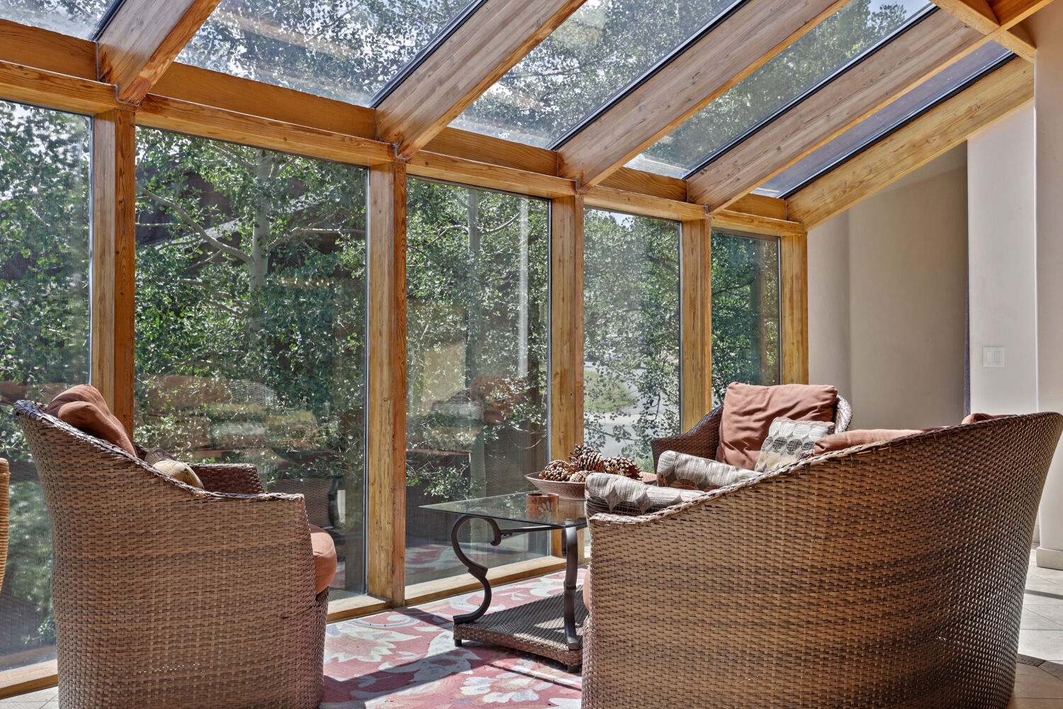 Step into your private sunroom where natural light pours through the glass ceiling and walls of windows frame lush garden views—your perfect spot to unwind with a book and a cup of tea.