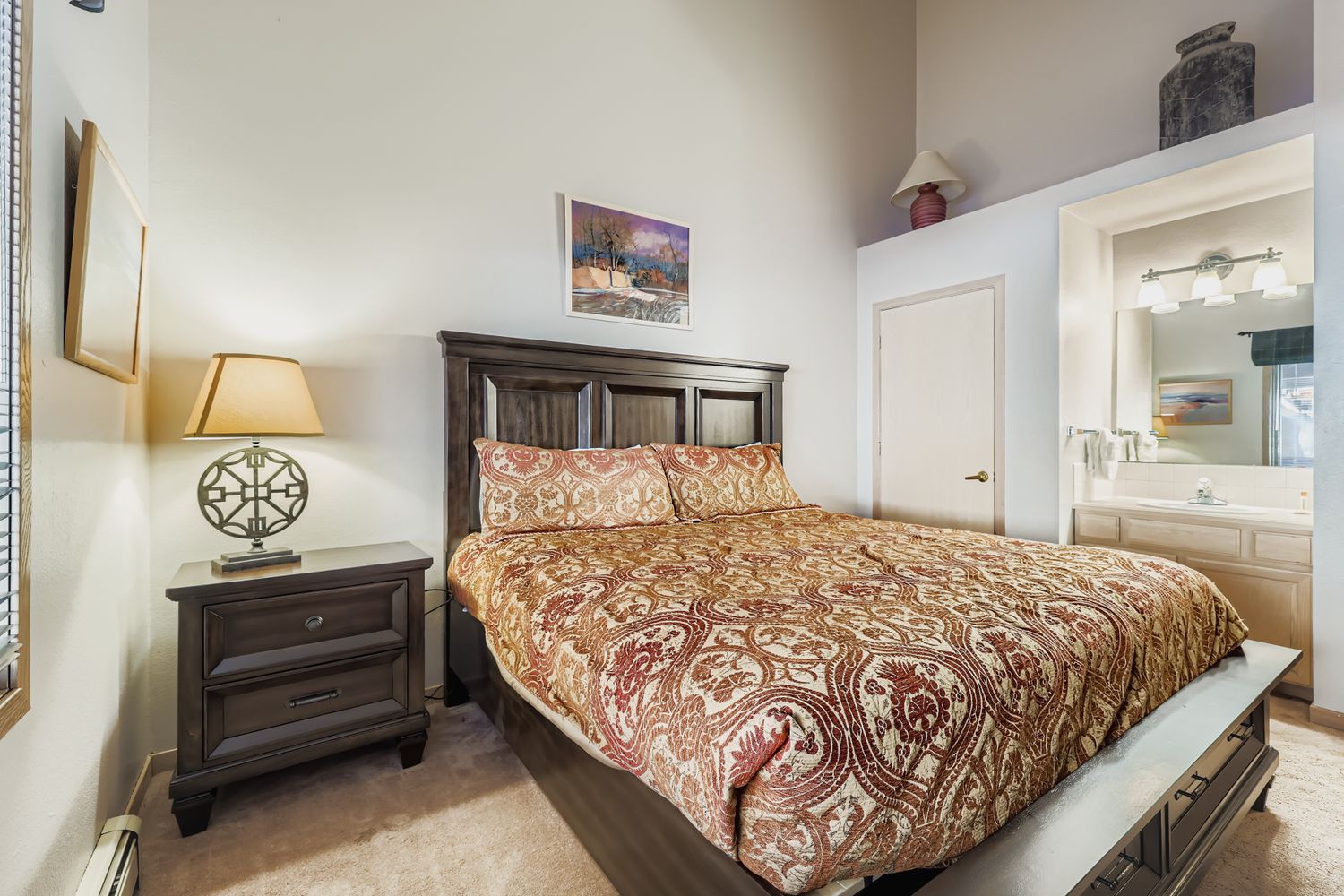 Unwind in your cozy bedroom featuring rich wood furnishings, warm paisley bedding, and thoughtful touches that create the perfect retreat.