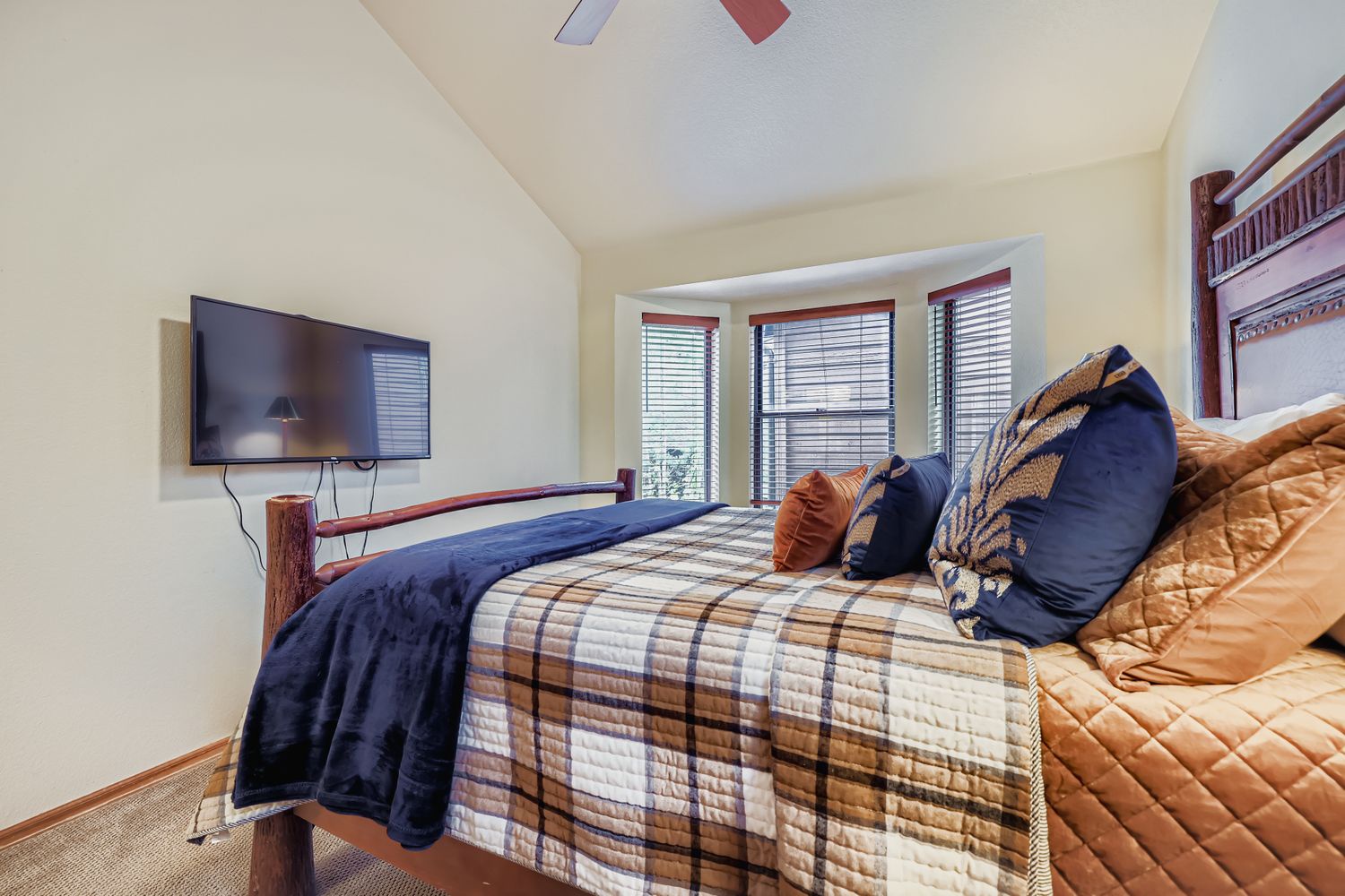 Sink into this cozy bedroom where plaid bedding and warm colors create your perfect mountain retreat sanctuary.