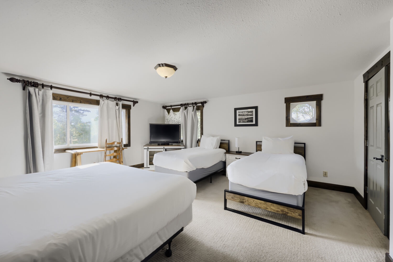 This bright, spacious room welcomes you with three comfortable beds dressed in crisp white linens, a cozy dining nook, and a flat-screen TV—perfect for relaxing after exploring the area together.