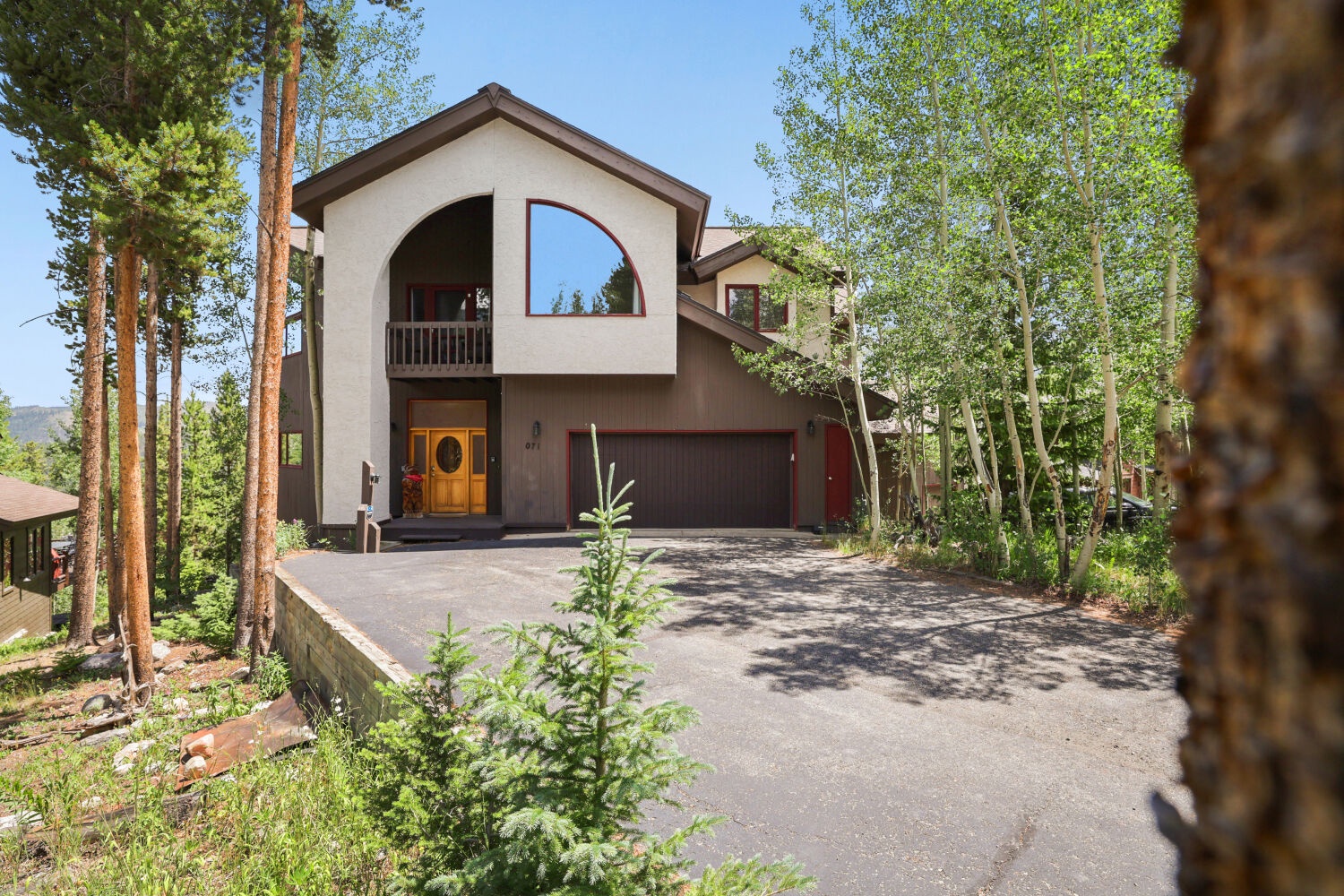 A distinctive mountain home set among tall pines and lush aspen groves, featuring a spacious driveway and convenient two-car garage for your arrival.