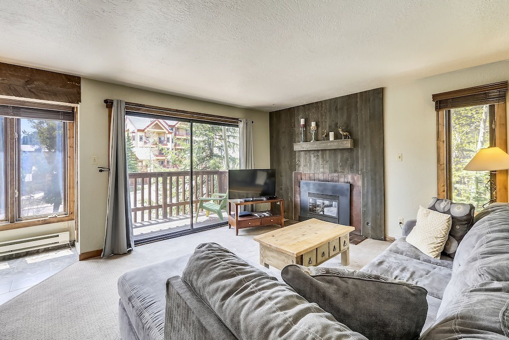 Relax in your spacious living room with cozy seating, warm fireplace, and bright windows opening to your private balcony overlooking the neighborhood.