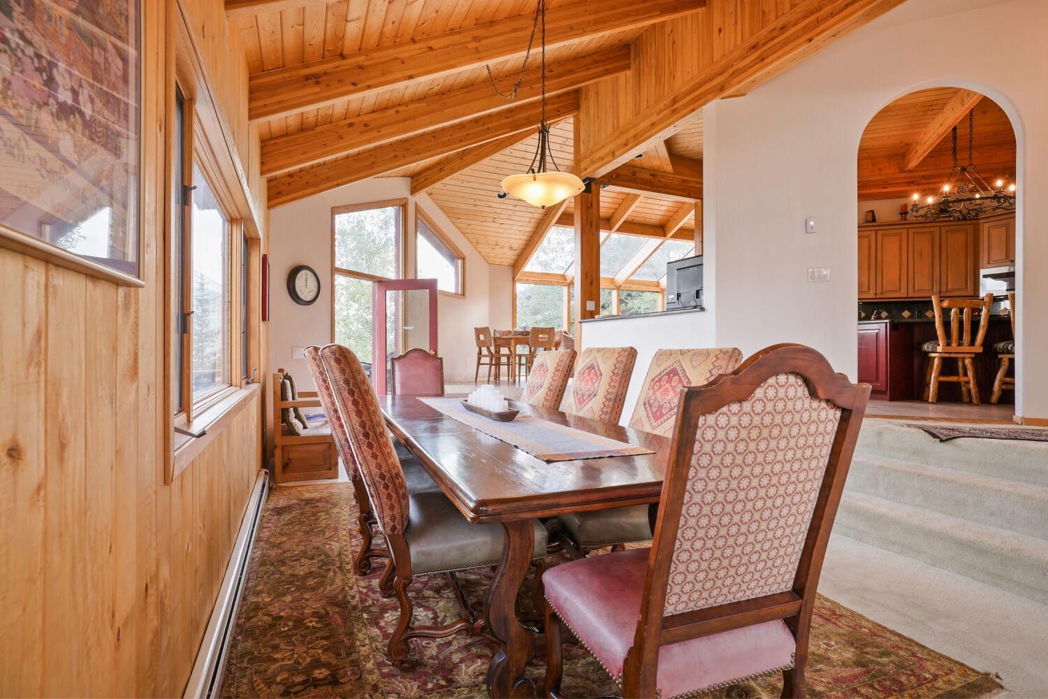 Gather around the grand dining table beneath soaring wood-beam ceilings, where sunlight streams through tall windows and natural warmth wraps around every meal you'll share together.