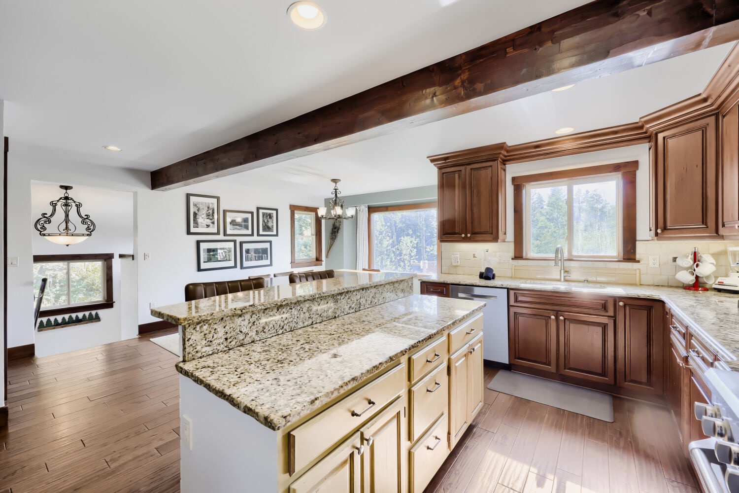 Your fully equipped gourmet kitchen features warm wood cabinetry, granite countertops, and a spacious island—perfect for preparing meals while natural light streams through multiple windows.