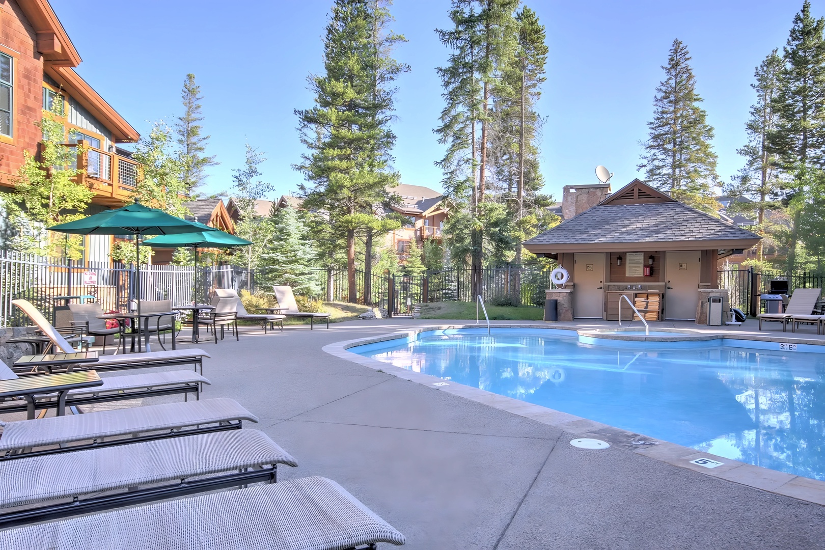 Dive into crystal-clear waters surrounded by towering pines. Your poolside lounging spot awaits with comfortable seating and mountain air.