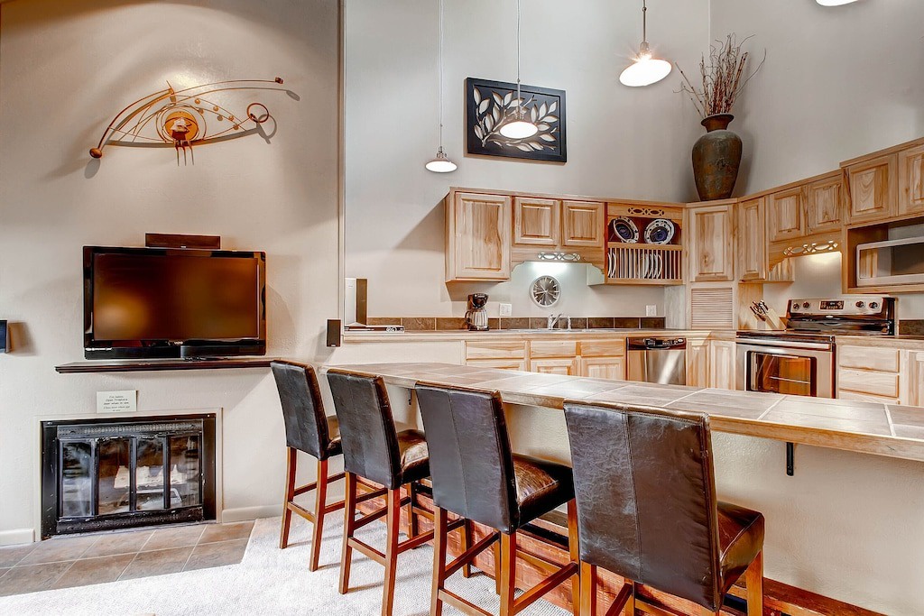 Gather around your spacious breakfast bar where warm wood finishes and modern appliances create the perfect spot for morning coffee or casual meals.