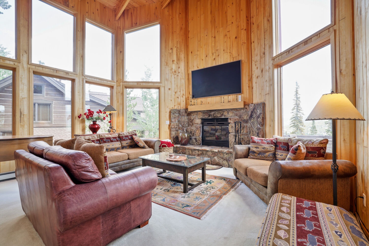 Sink into plush leather seating as sunlight pours through soaring windows, warming the natural wood walls and illuminating your mountain retreat with alpine charm and effortless comfort.