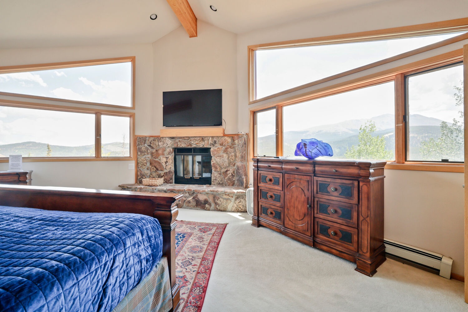 Wake up to sweeping mountain vistas through floor-to-ceiling windows, where your private stone fireplace and vaulted ceilings create a serene mountain retreat.