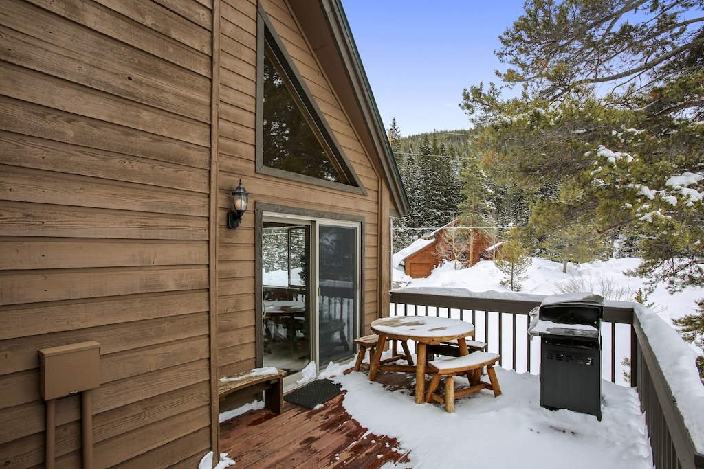 Cozy mountain cabin surrounded by snow-covered forest, offering winter views from private deck.
