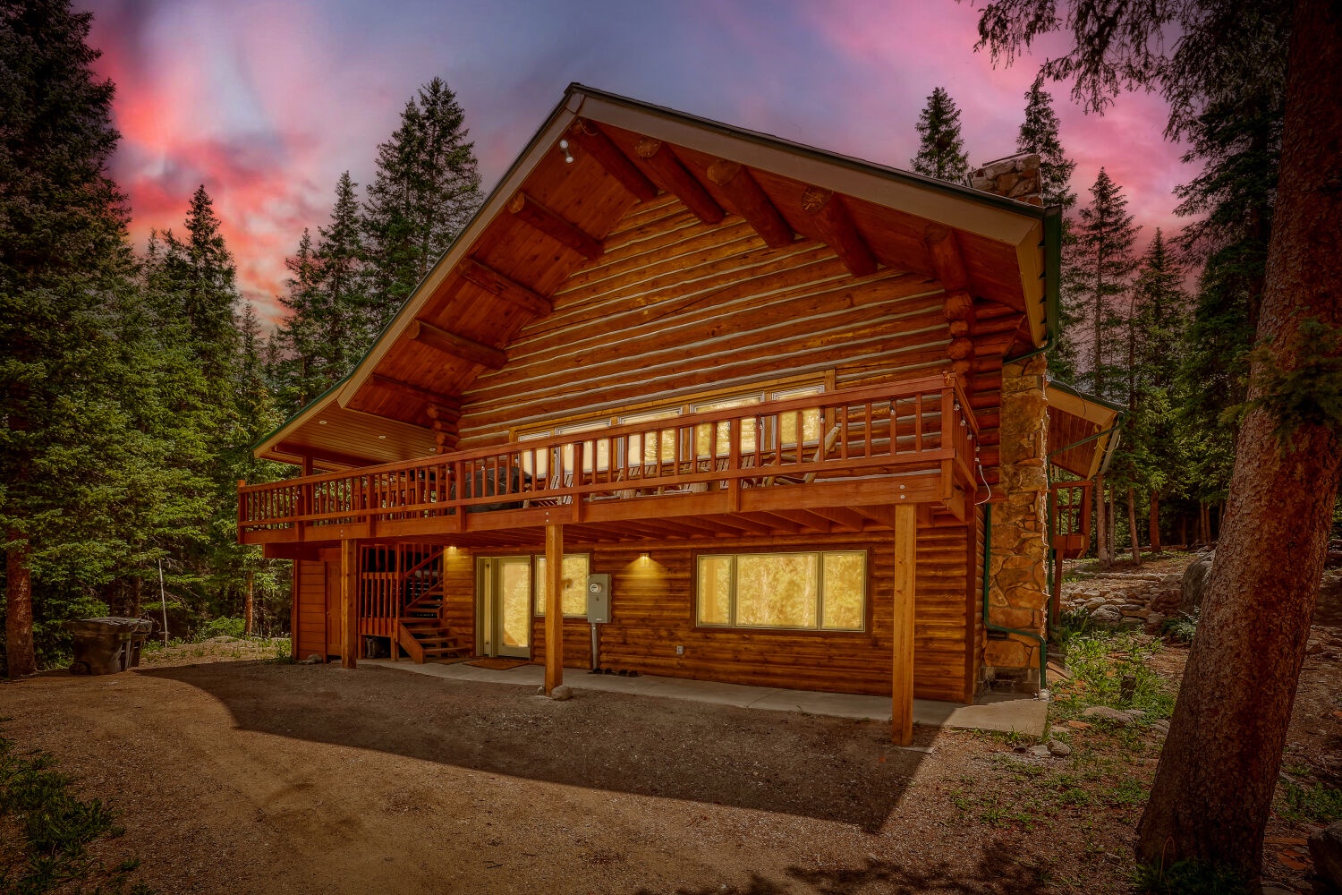 This beautiful log cabin nestled in towering pines welcomes guests at sunset with warm lighting and rustic mountain charm, offering a secluded forest retreat.