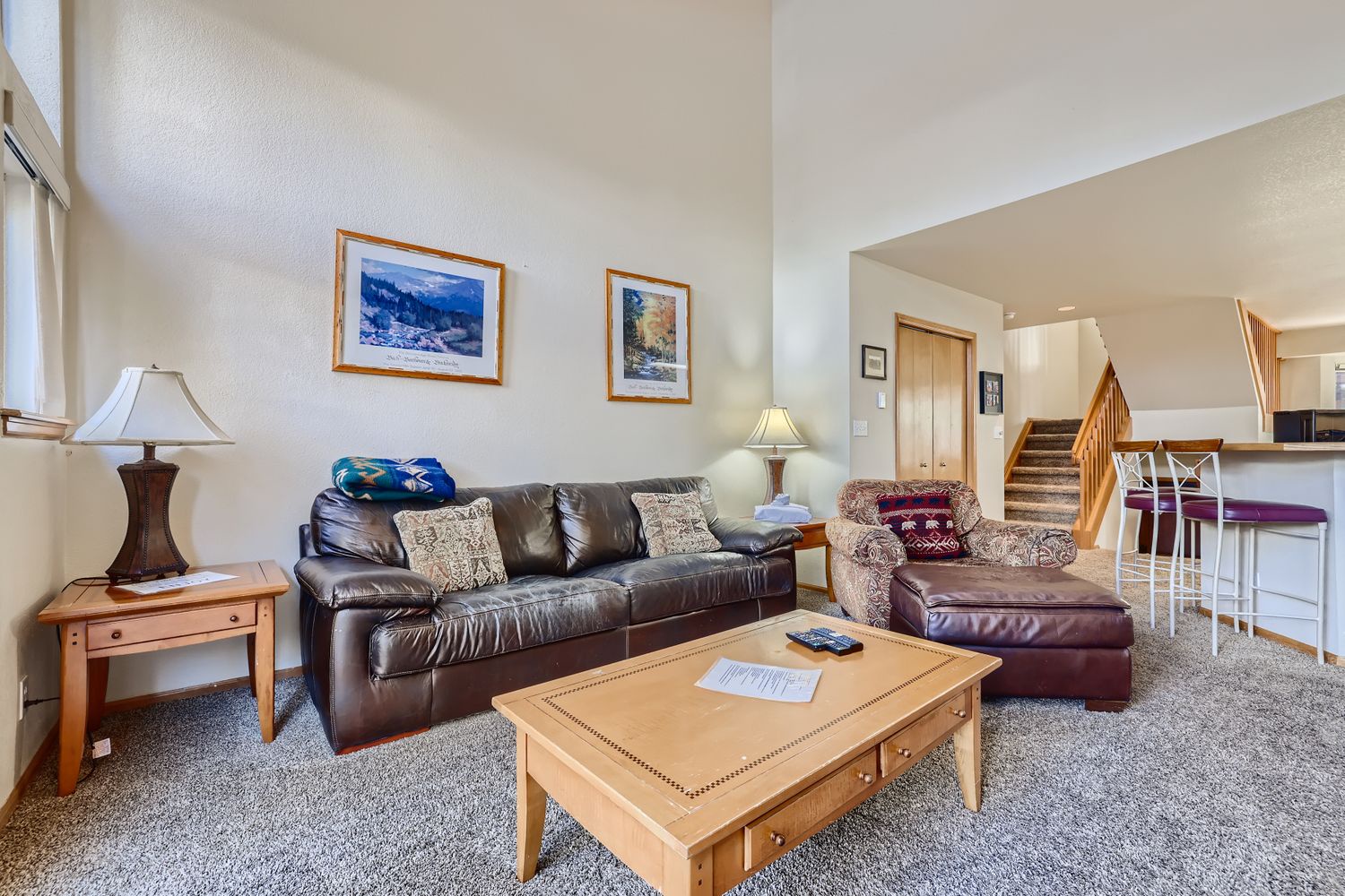 Relax in your spacious living room with comfortable leather seating, warm wood accents, and mountain artwork creating the perfect alpine getaway ambiance.